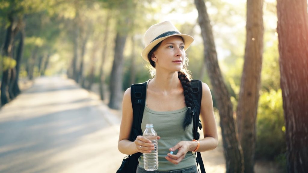 a woman in a hat is holding a water bottle