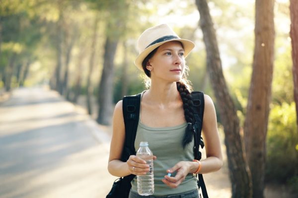 a woman in a hat is holding a water bottle