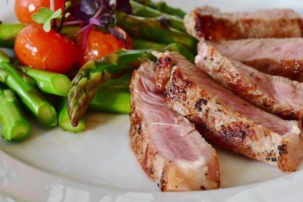 Close-up of grilled steak slices with asparagus and cherry tomatoes, perfect for a healthy meal.